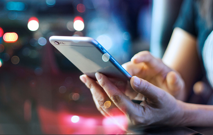 Hands holding a phone showing package tracking at night