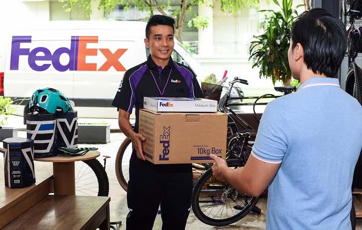 Courier handing a package to a customer beside a delivery van